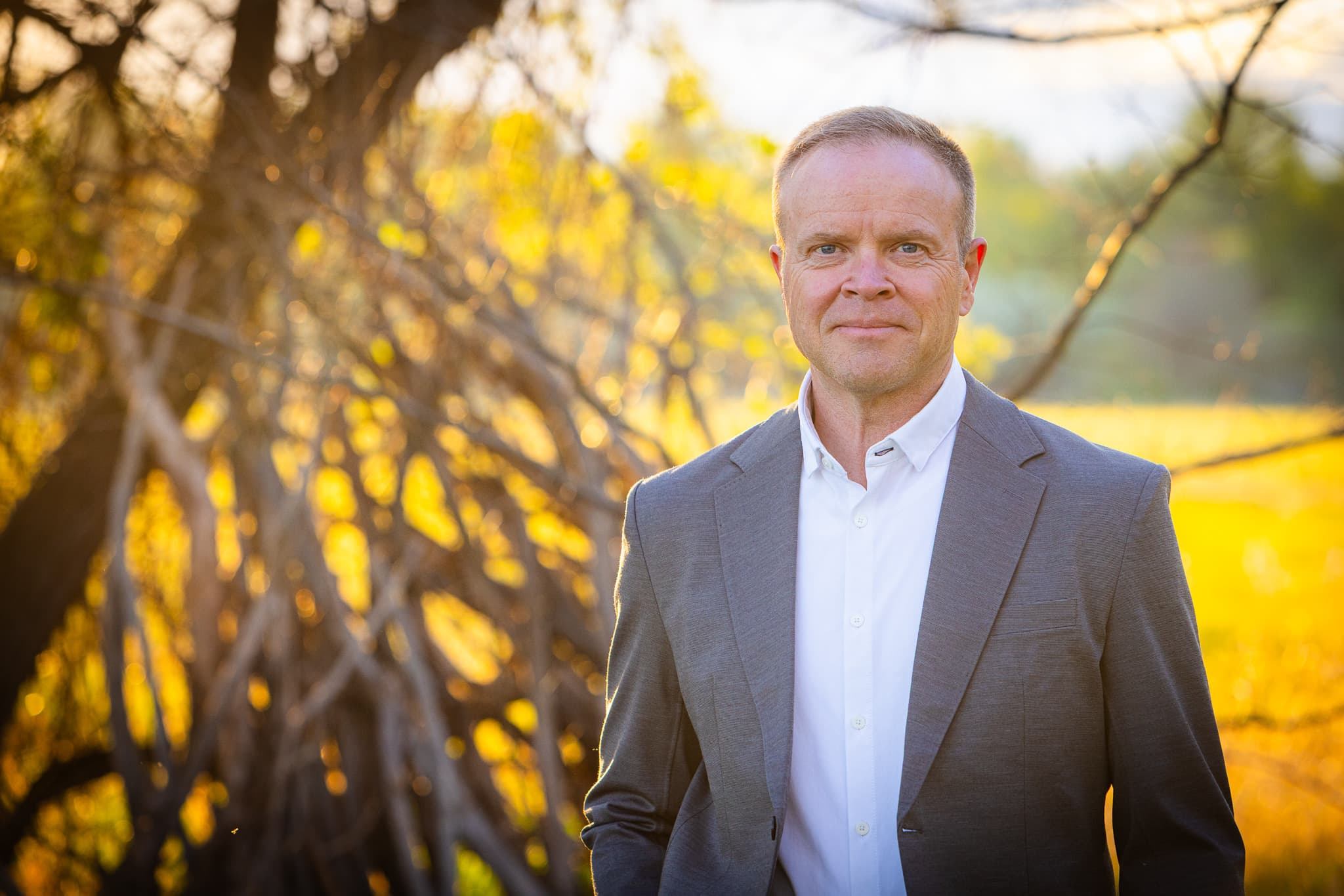 Dale Dixon standing outdoors in a gray jacket at golden hour